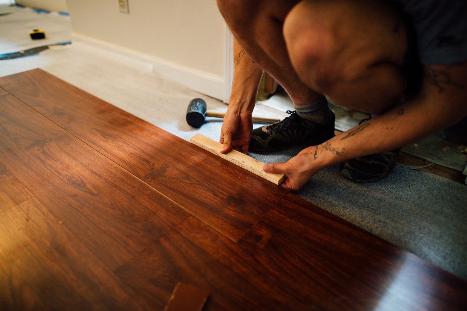 Installer fitting new plank flooring into place