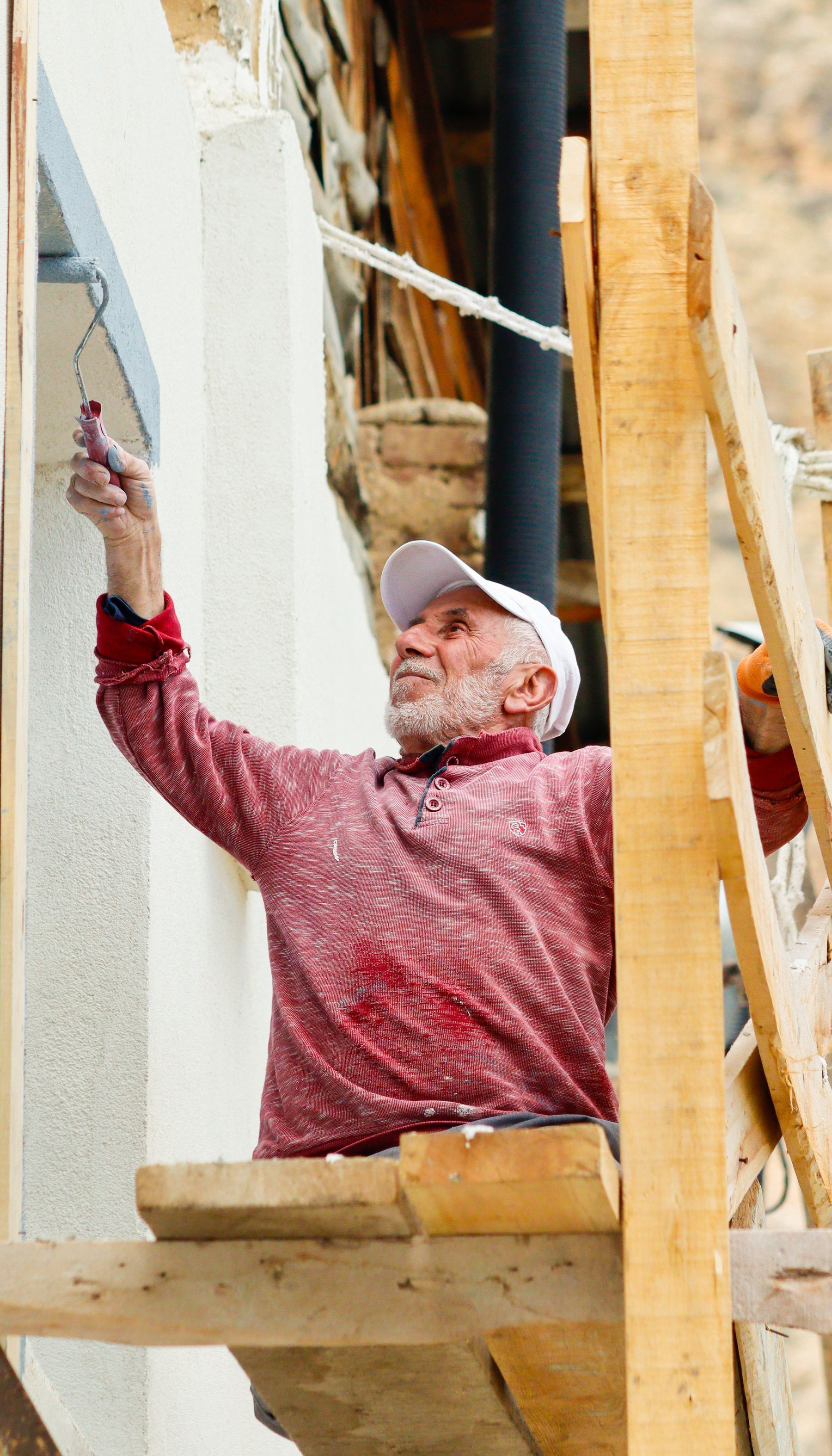 Painter on scaffolding painting an exterior wall