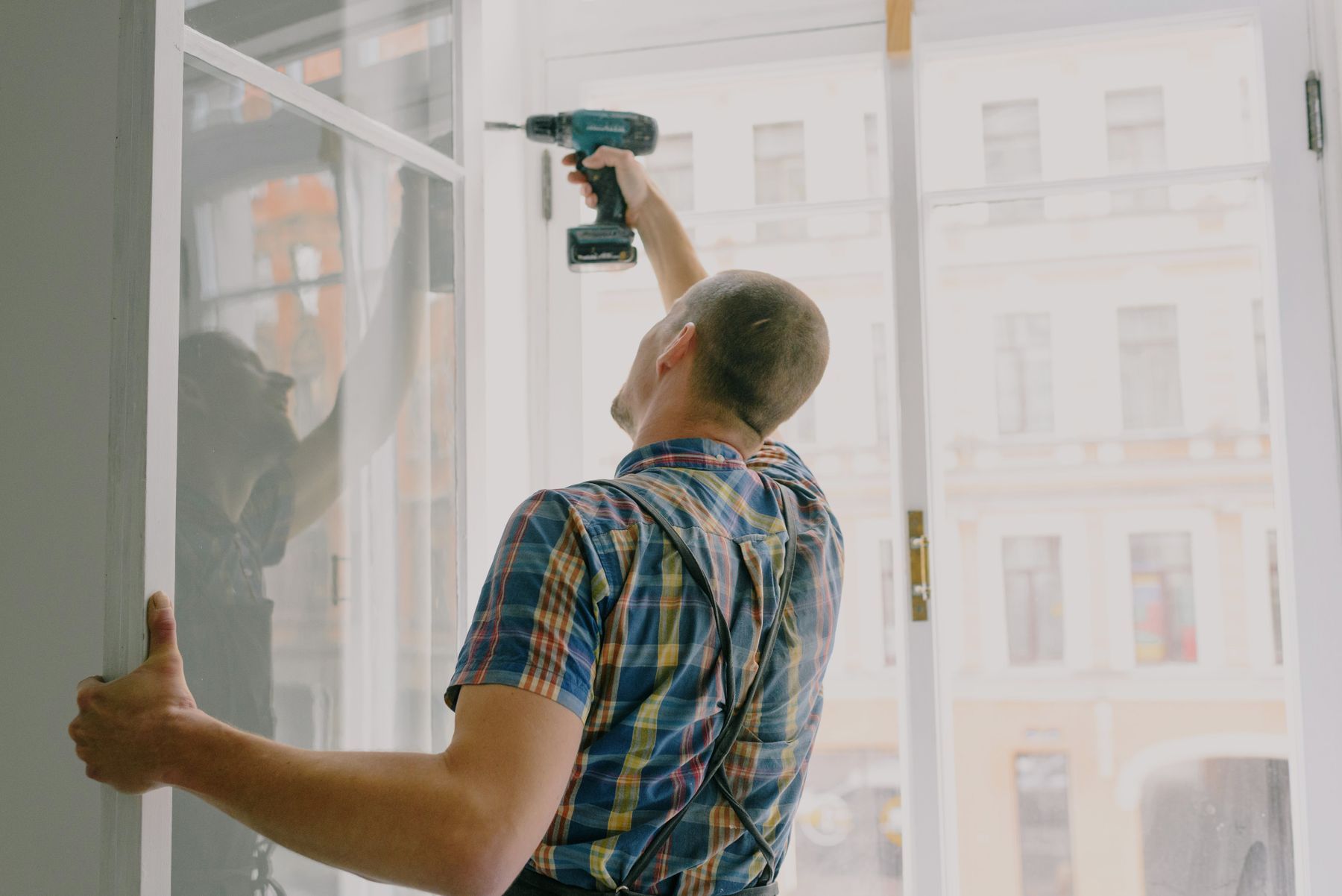 Handyman using a drill to install a window frame